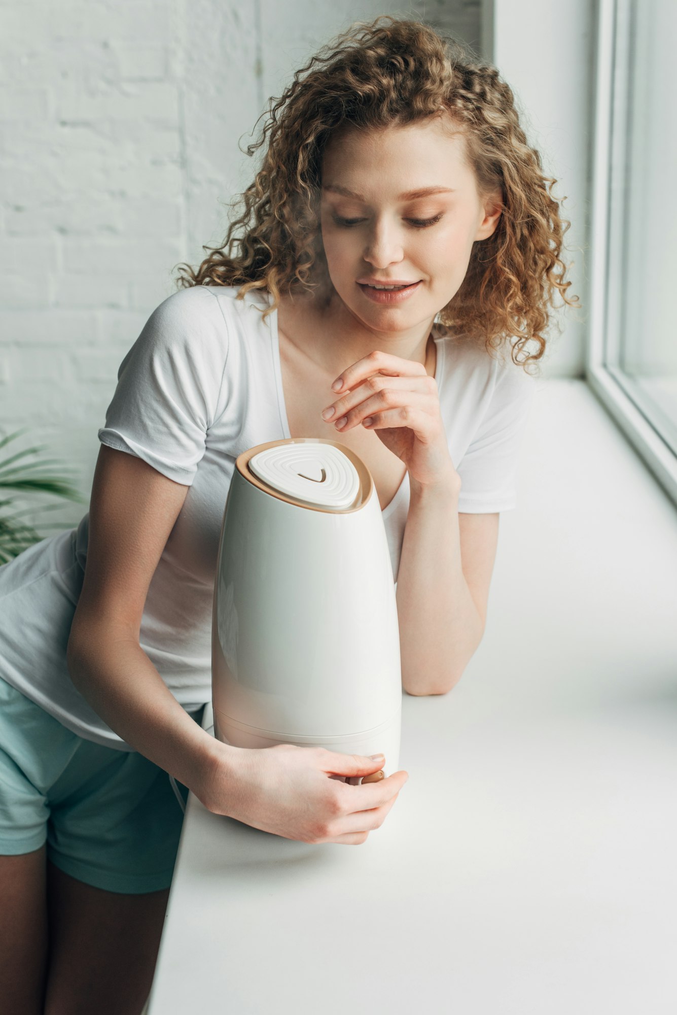 beautiful happy girl with air humidifier on windowsill