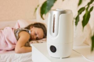 Cute little girl sleeping in bedroom with air humidifier.